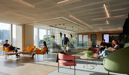 Open lounge space at MYO Liverpool Street featuring colourful seating, city views, integrated planting and members relaxing, reading and working throughout the space.