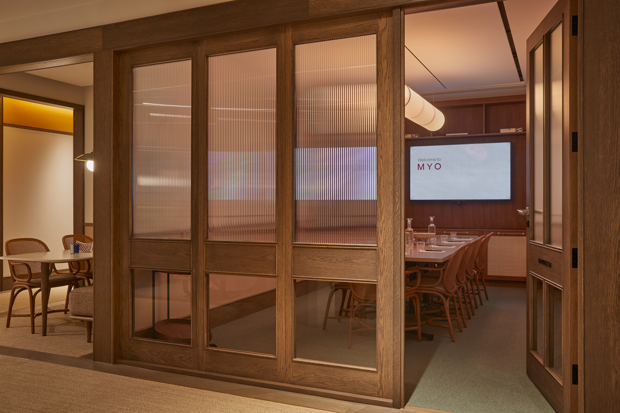 Contemporary private meeting rooms with glazed timber partitions, conference tables, presentation screens and warm wood finishes in a modern workspace.