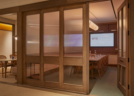 Contemporary private meeting rooms with glazed timber partitions, conference tables, presentation screens and warm wood finishes in a modern workspace.