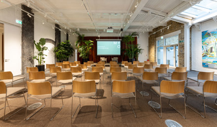 The Stables event space at MYO King's Cross set up in theatre style, featuring presentation facilities, natural light, exposed brickwork and biophilic design elements.