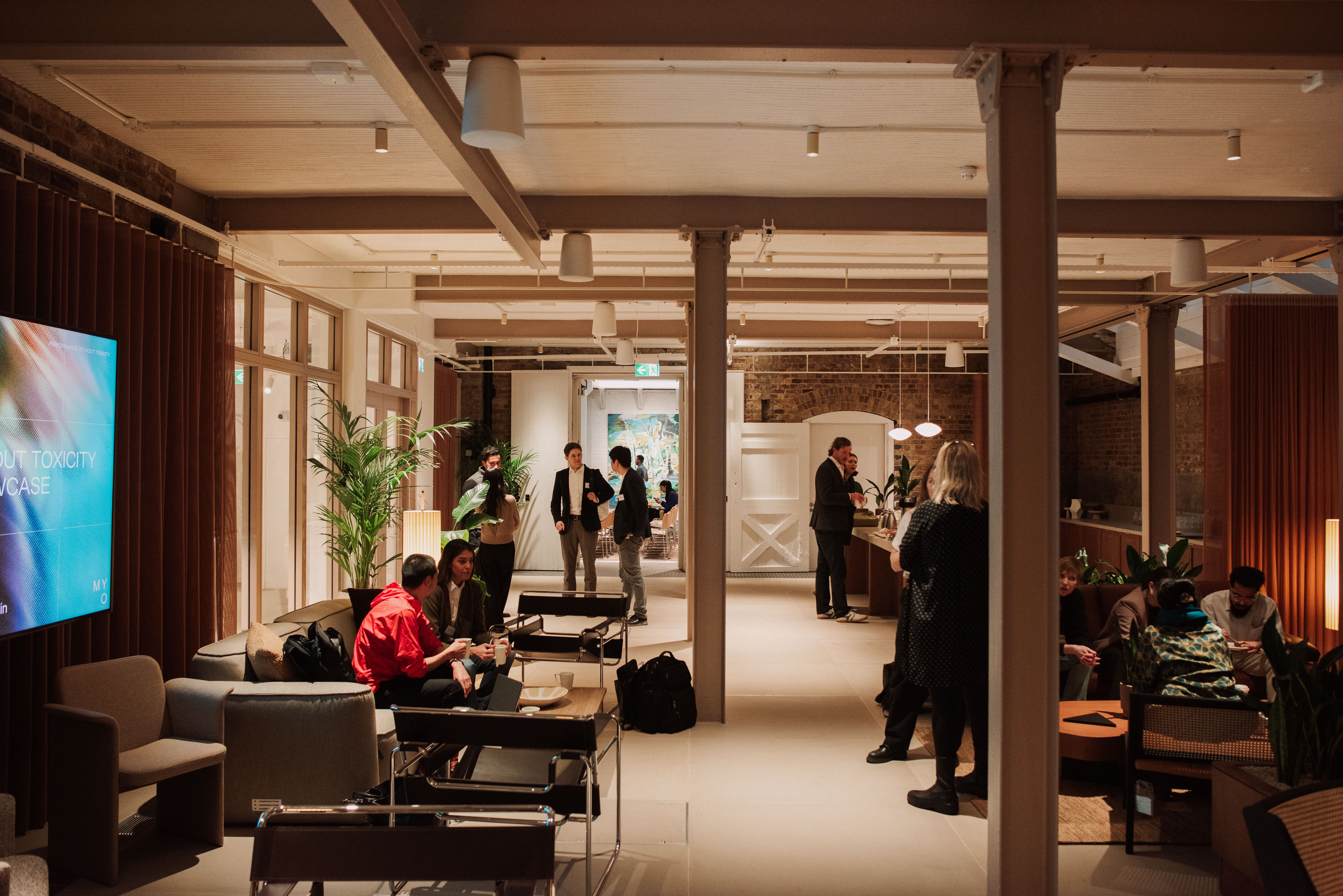 A contemporary communal lounge with people socialising, comfortable seating, a coffee bar and open-plan workspace interiors.