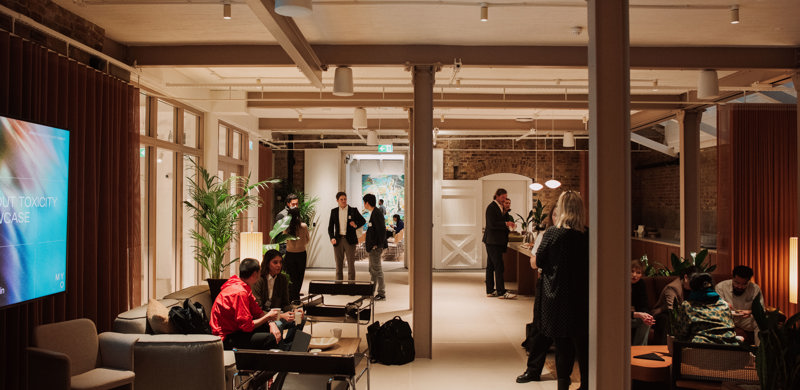 A contemporary communal lounge with people socialising, comfortable seating, a coffee bar and open-plan workspace interiors.