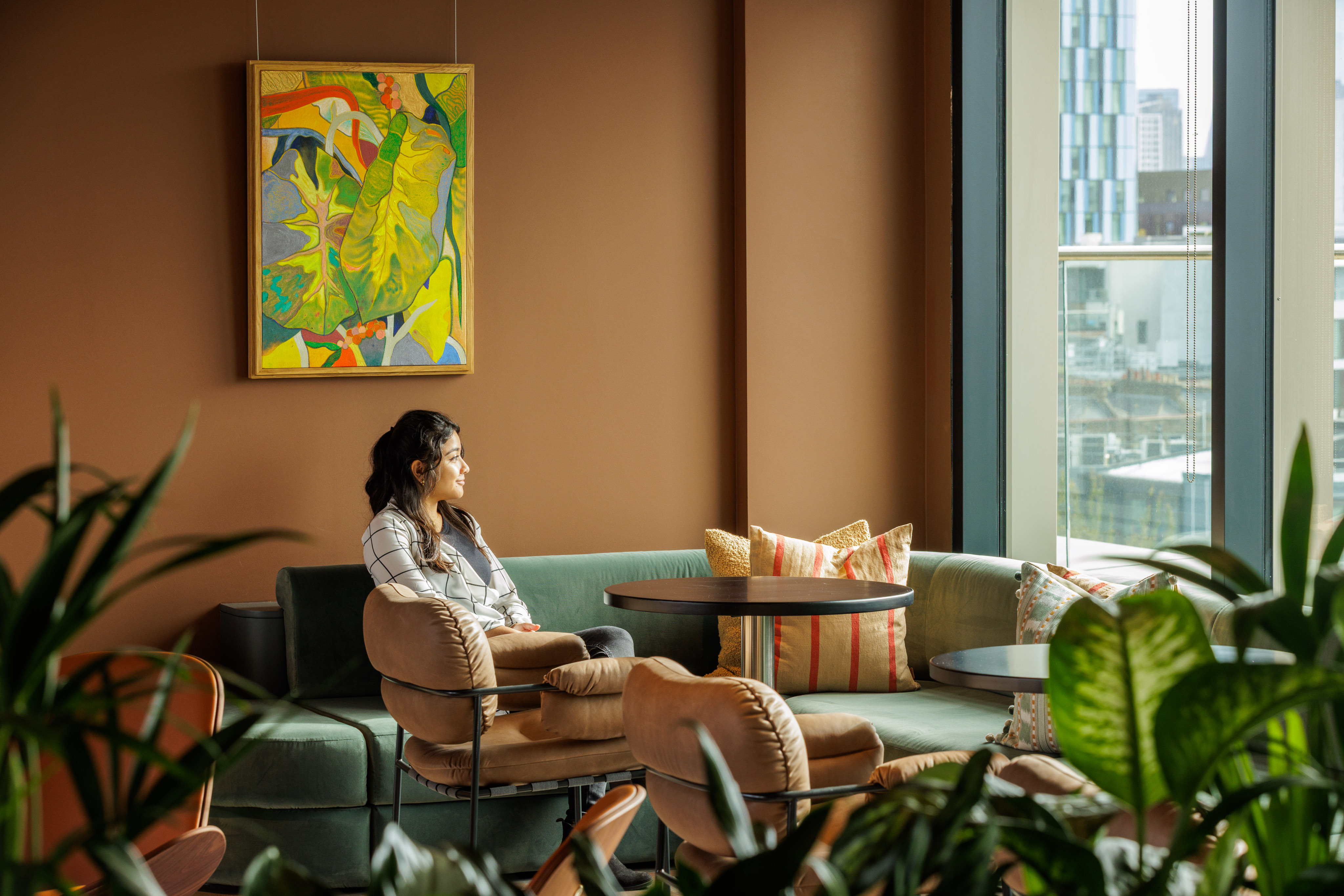 Professional relaxing in a comfortable lounge area at MYO King's Cross with soft seating, planting and views across the city.